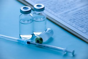 Medical vials and syringe beside clinical documentation